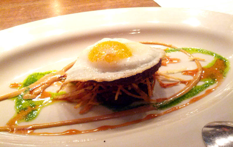 Girl and the Goat's Fried Egg on Top of Pork Cheek on a Fancy Sauced Plate